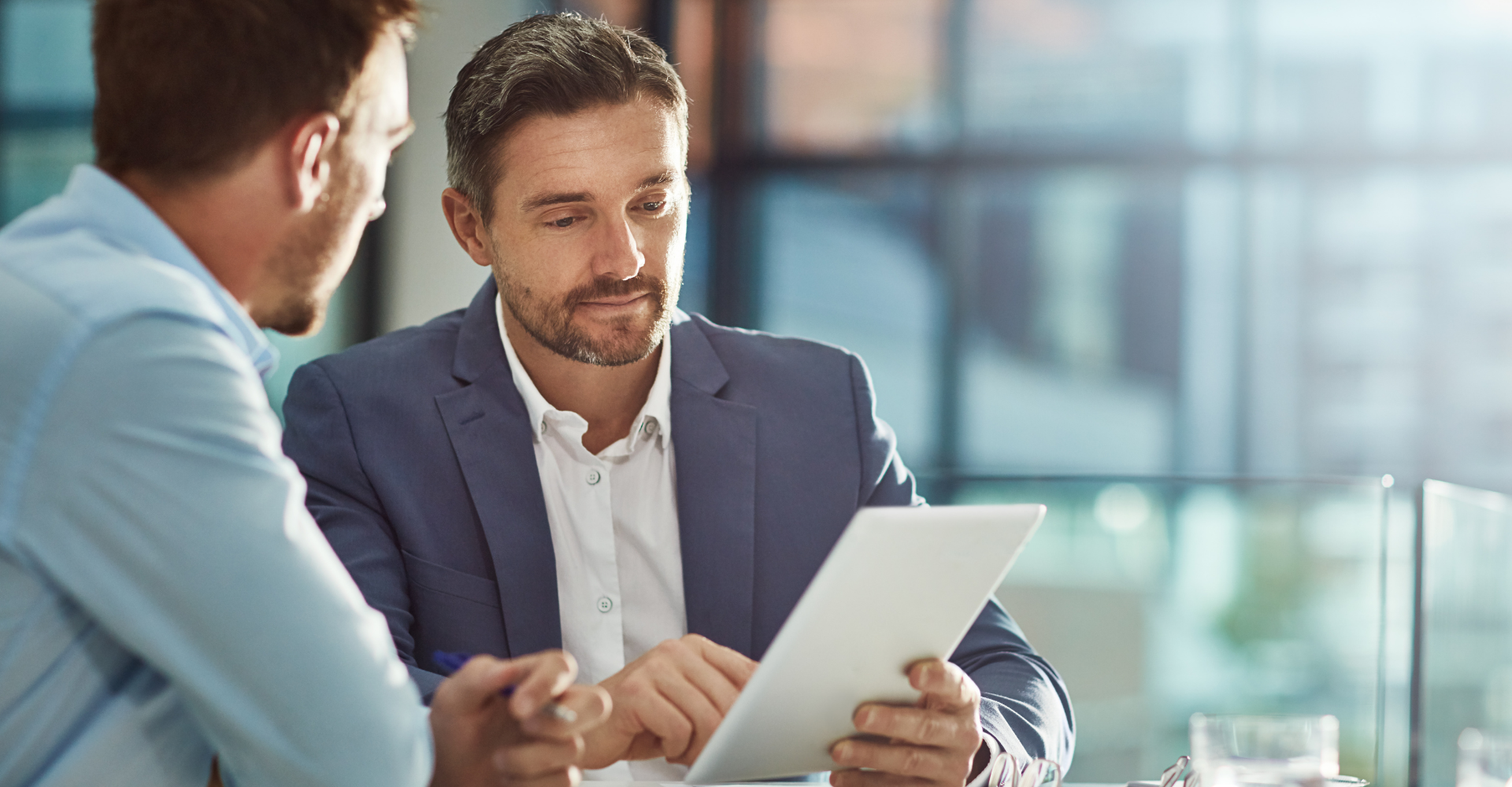 Man met een tablet in zijn hand, er zit een man links van hem